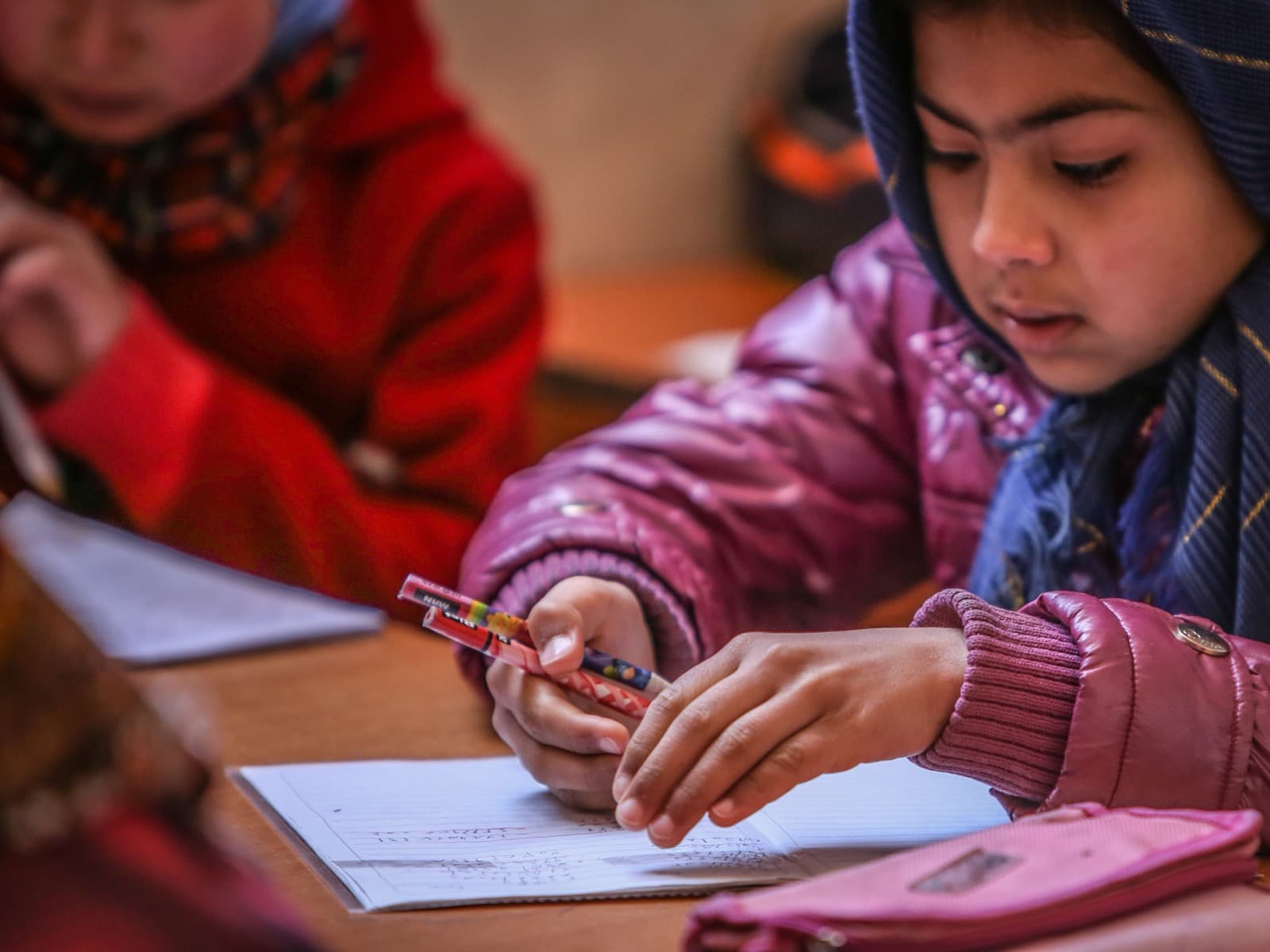 Jeune élève concentrée en train d'écrire dans son cahier