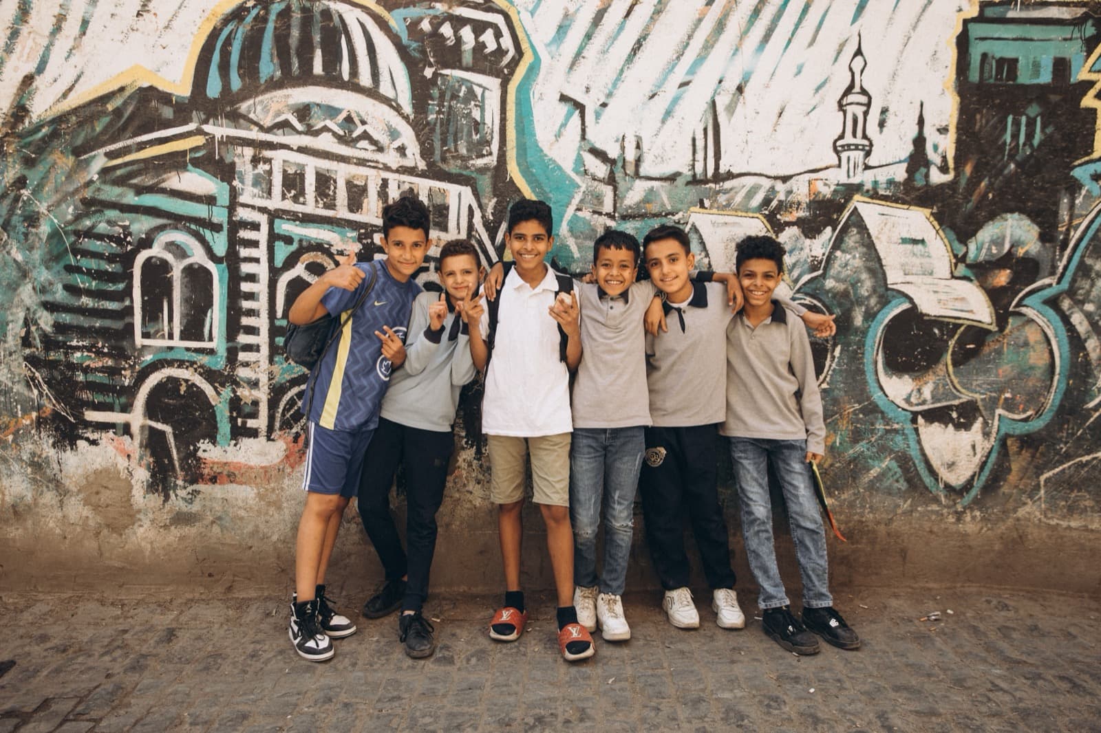 Groupe d'élèves marocains souriants devant une fresque murale